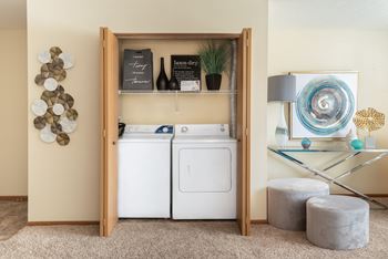 A laundry room with a washer and dryer, a glass table, and decorative items.